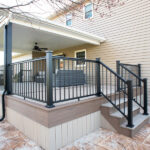 new deck with partial coverage, stairs, and black railing