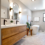 primary bathroom with bathtub, wooden sinks, and large mirrors