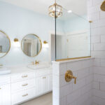 bathroom with a walk in shower, two mirrors, and white sinks