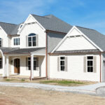 new home with two garage doors, front porch, and columns