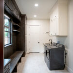 laundry room with wooden storage and black appliances