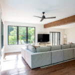 living room with sectional couch, tv, and ceiling fan