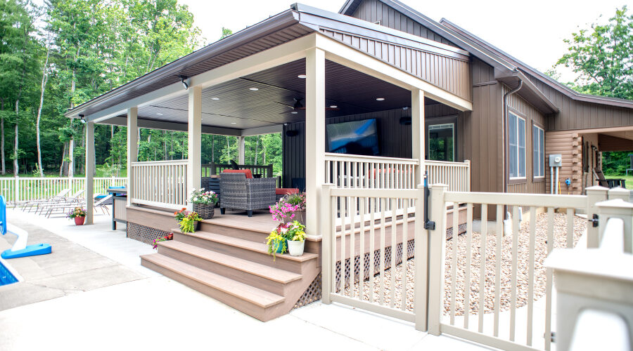 outdoor living space with roof, vinyl railings, and tv