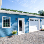 garage addition with two white garage doors and blue siding