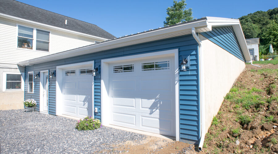 DSC_0143 garage addition with blue siding and two white garage doors