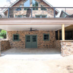 living space under deck with stone veneer, green doors and windows, and ceiling fan