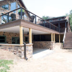 outdoor living space with second story deck, stone veneer, cable railings, and English Walnut decking