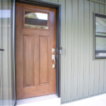 new wooden front door and green siding